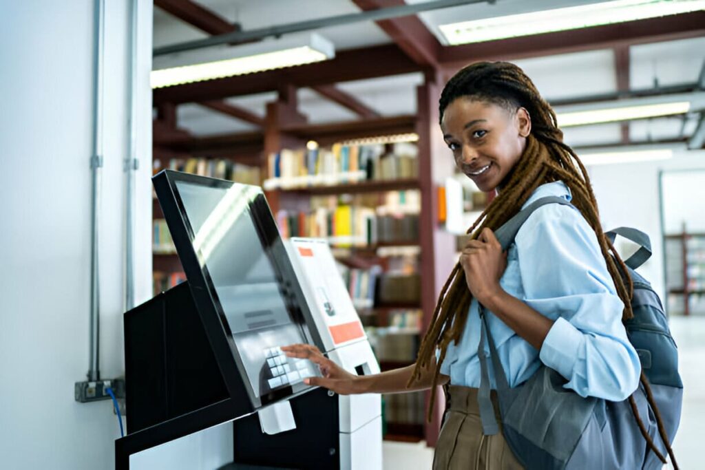 Female student in front of a machine, dressed in a blue outfit and holding a clipboard